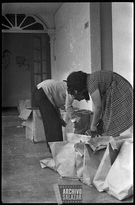 Canal 6 TV, Primera Maratón, 1961. Tres personas organizan regalos en fundas de papel en corredores de una casa estilo colonial.