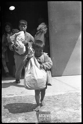 Canal 6 TV, Primera Maratón, 1961. Niño descalzo en primer término,  y otros niños saliendo de instalaciones del canal con regalo en funda de papel.