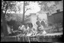 Mujer con niños no identificados posando con perros en patio de casa.