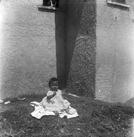 Niña sentada en patio con cesped.
