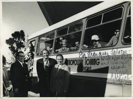 Fotografía autografiada del actor estadounidense, Gregory Peck, con bus de turismo en fondo.