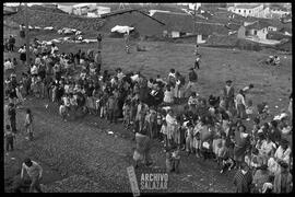 Canal 6 TV, Primera Maratón, 1961. Grupo de personas de sectores populares haciendo fila. Ropa colgada en arbustos y ciudad al fondo.