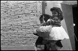 Canal 6 TV, Primera Maratón, 1961. Mujer cargando a niña con regalo en funda de papel saliendo de instalaciones del canal.