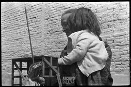 Canal 6 TV, Primera Maratón, 1961. Mujer cargando a niña con regalo en funda de papel saliendo de instalaciones del canal.